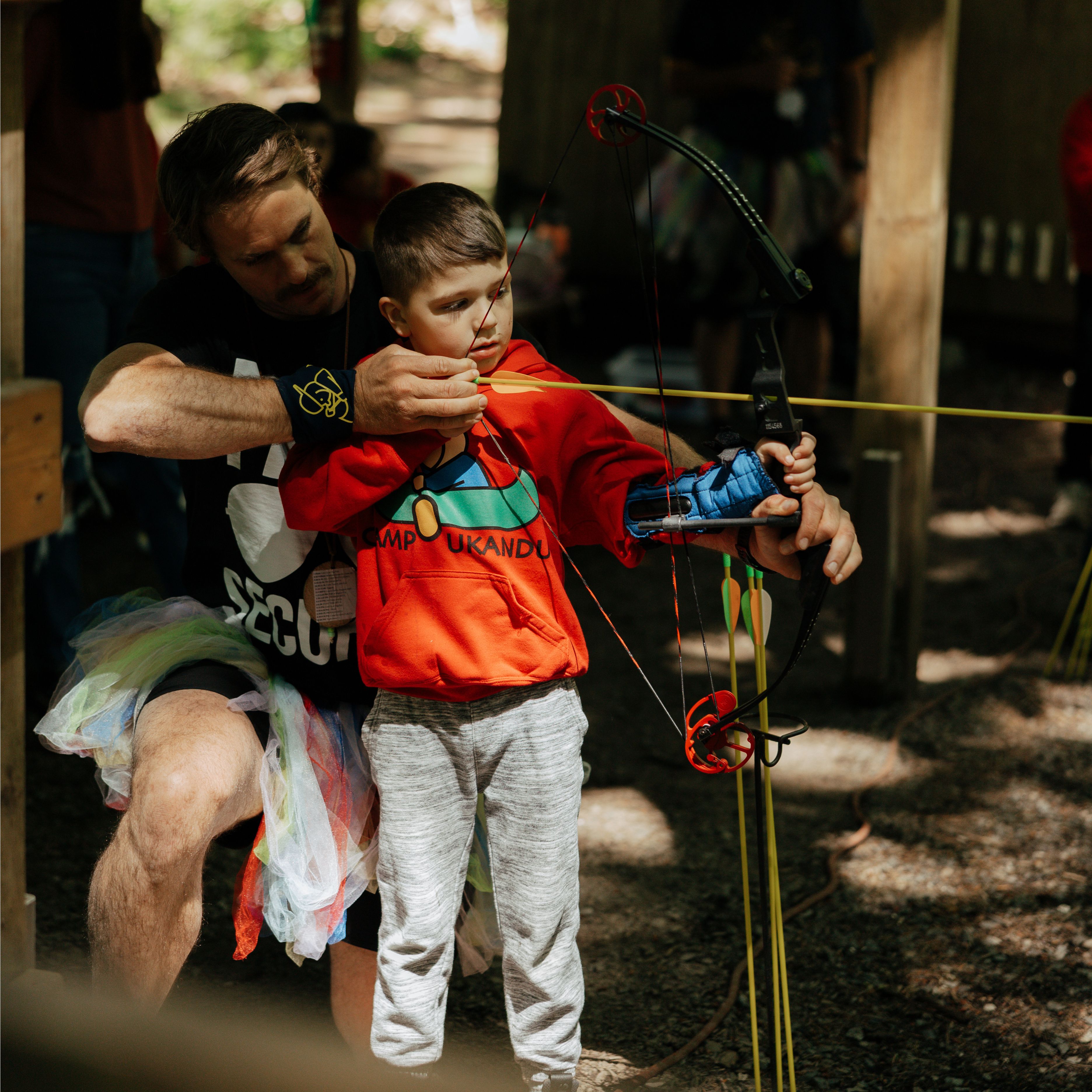 Volunteer helping a camper with archery